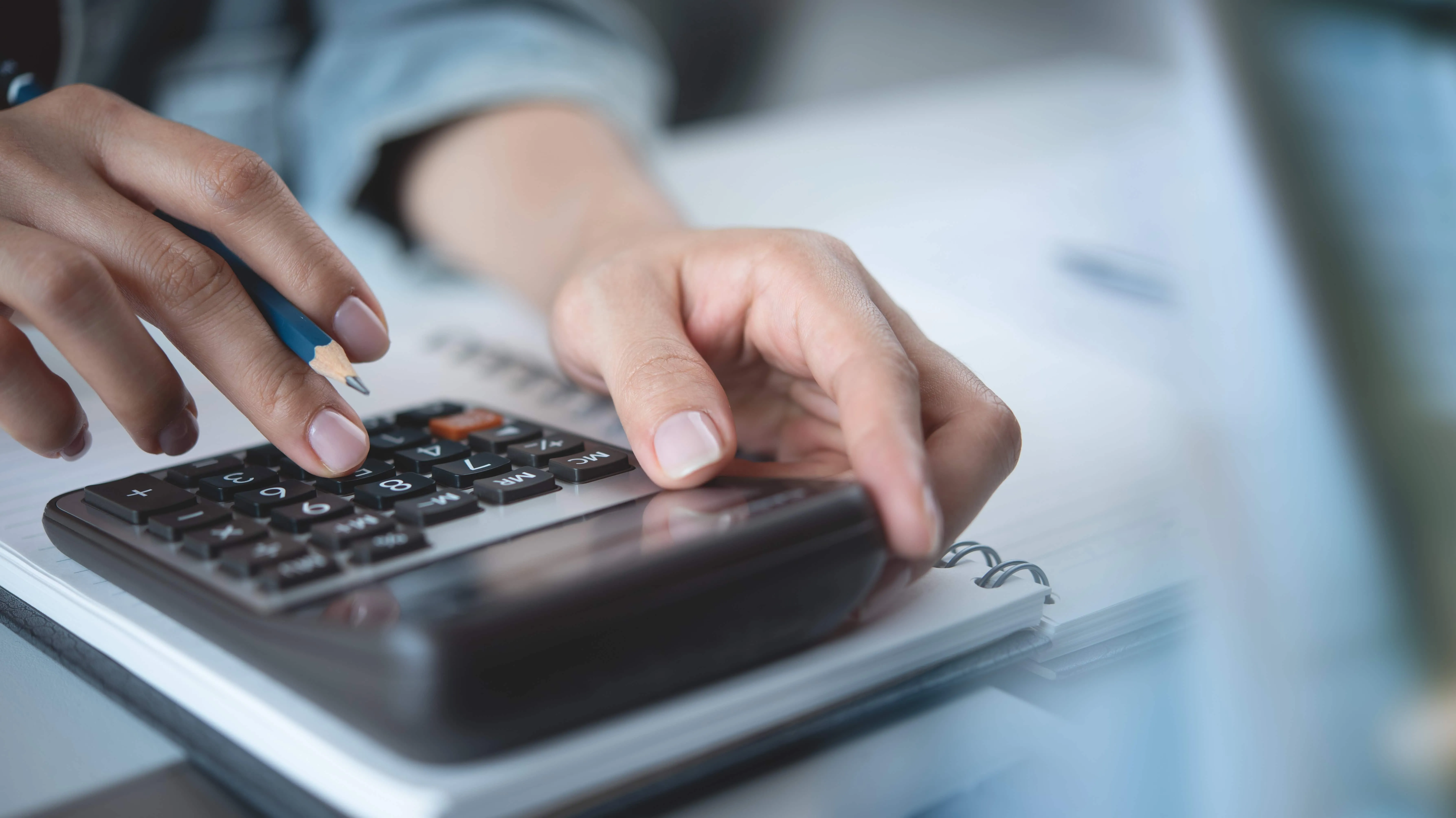 Person using a calculator and pencil to calculate costs associated with orthodontic care in West Valley City, UT.